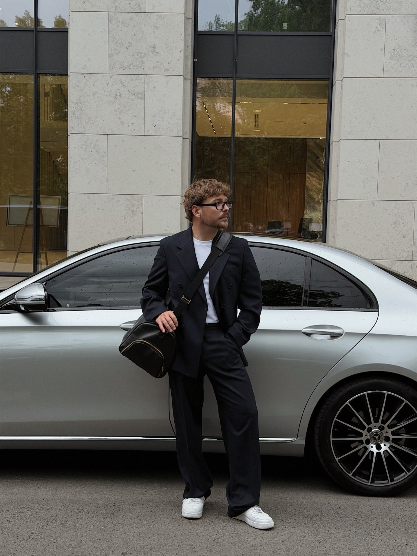 Павло у чорному костюмі біля сірого Mercedes. Місто.